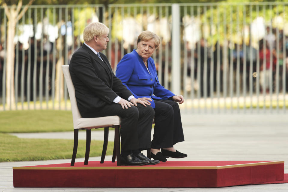 German Chancellor Angela Merkel sits alongside Britain's Prime Minister Boris Johnson during a welcome ceremony with military honors for a meeting at the Chancellery in Berlin, Germany, Wednesday, Aug. 21, 2019.( J'rg Carstensen/dpa via AP)