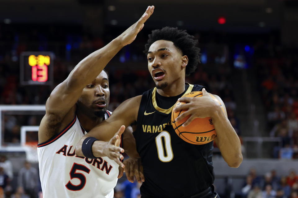 Vanderbilt guard Tyrin Lawrence (0) drives to the basket around Auburn forward Chris Moore (5) during the first half of an NCAA college basketball game, Wednesday, Jan. 31, 2024, in Auburn, Ala. (AP Photo/ Butch Dill)