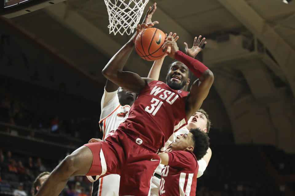 Washington State guard Kymany Houinsou, center, grabs a rebound in front of Oregon State's Chol Marial, left, and Tyler Bilodeau, right rear, and next to Washington State's Isaiah Watts (12) during the first half of an NCAA college basketball game Thursday, Feb. 8, 2024, in Corvallis, Ore. (AP Photo/Amanda Loman)