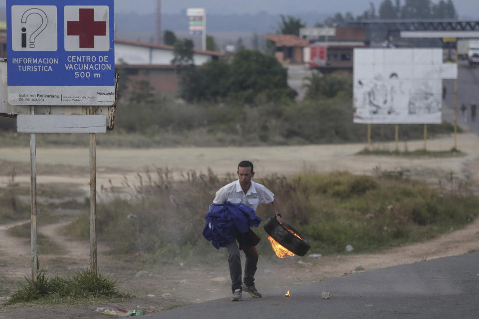 A protestor gets ready to hurl a burning tire during a protest at the border between Brazil and Venezuela, in Pacaraima, Roraima state, Brazil Saturday, Feb.23, 2019. Tensions are running high in the Brazilian border city of Pacaraima. Thousands remained at the city's international border crossing with Venezuela to demand the entry of food and medicine.(AP Photo/Ivan Valencia)