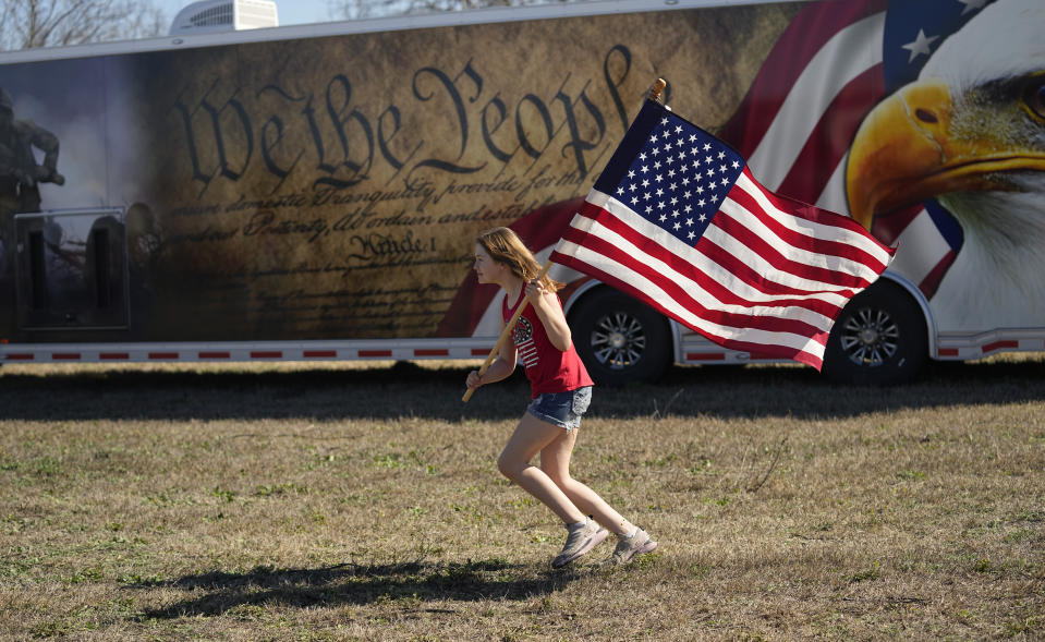 Lola Lee, from New Mexico, runs with a U.S. flag during a "Take Our Border Back" convoy and rally, Saturday, Feb. 3, 2024, in Quemado, Texas. (AP Photo/Eric Gay)