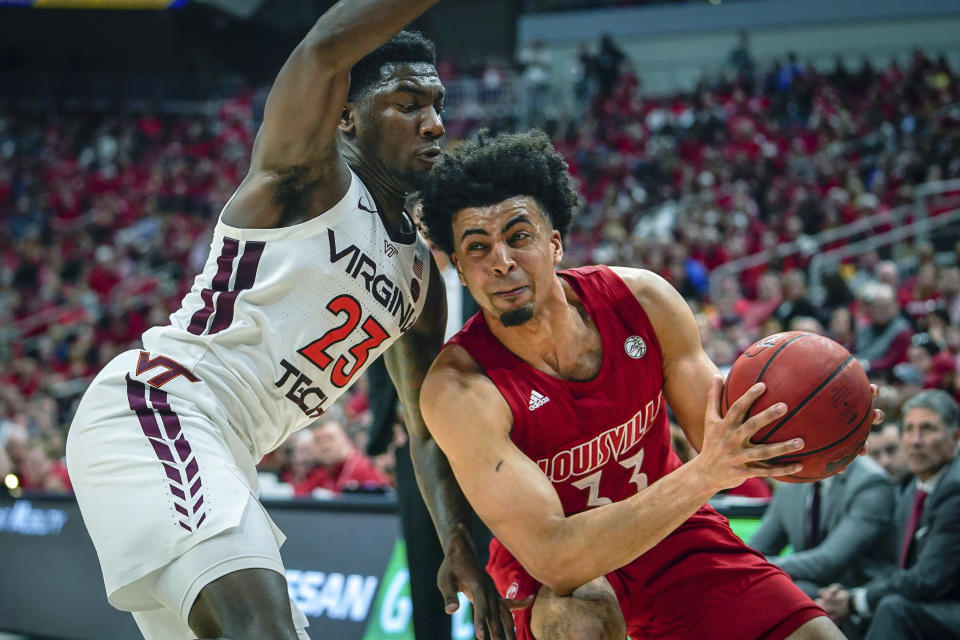 Louisville forward Jordan Nwora (33) dribbles past Virginia Tech guard Tyrece Radford (23) during the second half of an NCAA college basketball game, Sunday, March 1, 2020 in Louisville, Ky. (AP Photo/Bryan Woolston)