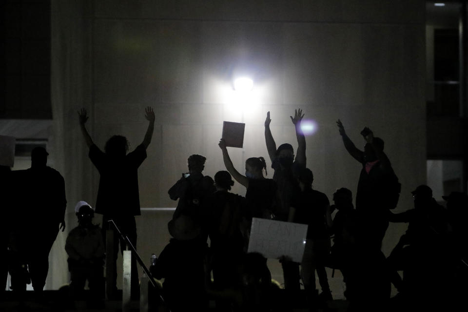 Protesters raise their hands in front of a line of police officers during a rally Monday, June 1, 2020, in Las Vegas, over the death of George Floyd, a black man who was in police custody in Minneapolis. (AP Photo/John Locher)