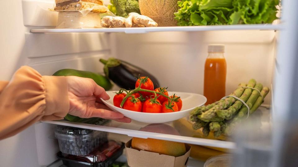 PHOTO: Woman taking out a tomato plate from a refrigerator at home. (STOCK PHOTO/Getty Images)