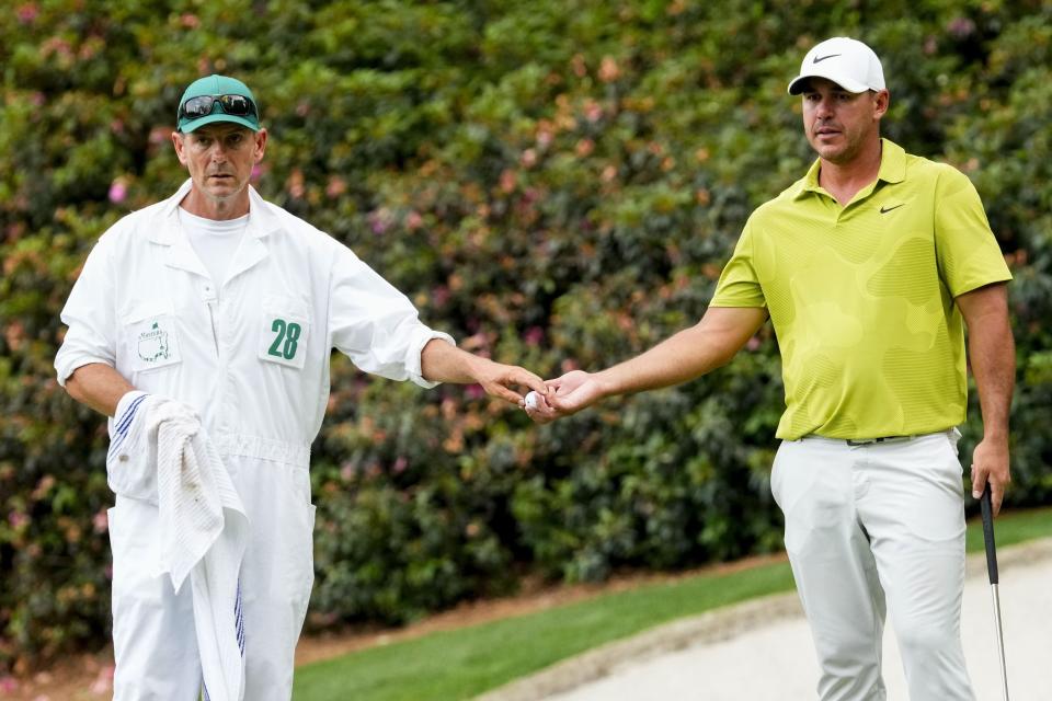 Brooks Koepka (right) gets his golf ball from caddie Ricky Elliot on the 13th green on Thursday.