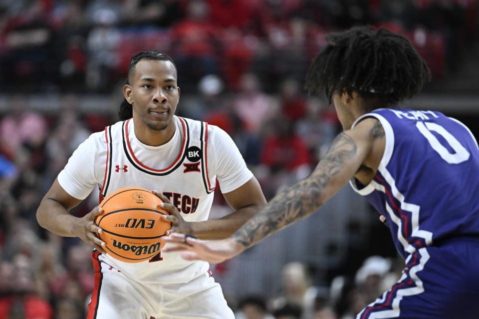 Texas Tech guard Lamar Washington, left, controls the ball in front of TCU guard Micah Peavy (0) during the first half of an NCAA college basketball game Tuesday, Feb. 20, 2024, in Lubbock, Texas. (AP Photo/Justin Rex)