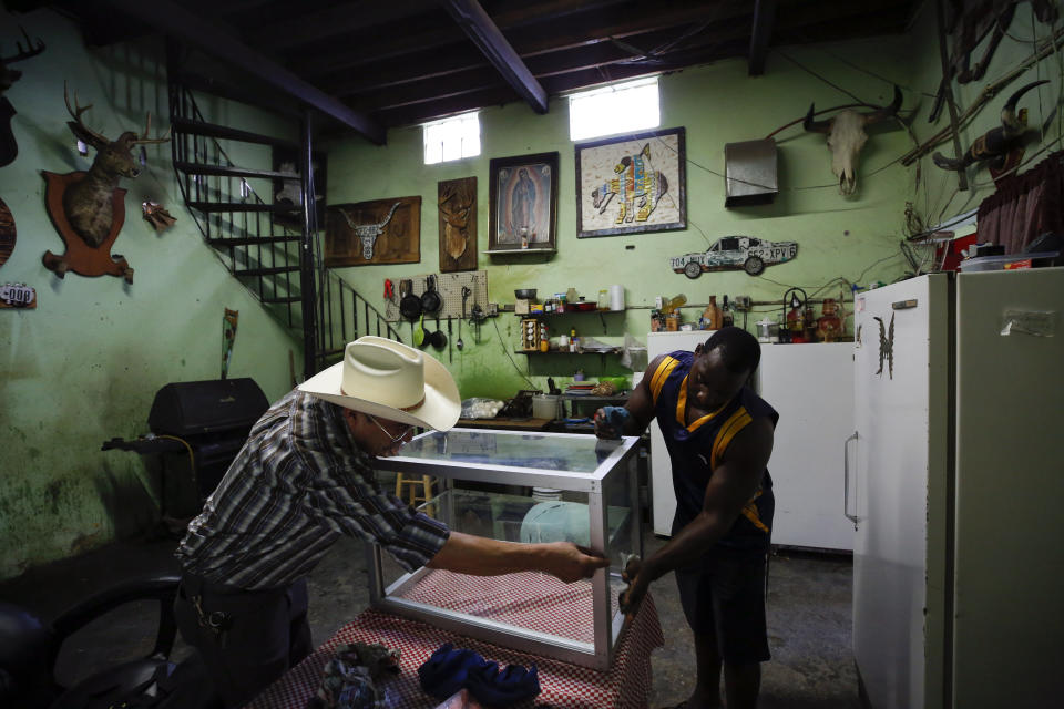 In this July 30, 2019, photo, Desidero Ojeda, left, of Texas, works with Alphat, of Uganda in repairing a display case at Ojeda's corner store near El Buen Pastor shelter for migrants, where Alphat is staying, in Cuidad Juarez, Mexico. (AP Photo/Gregory Bull)