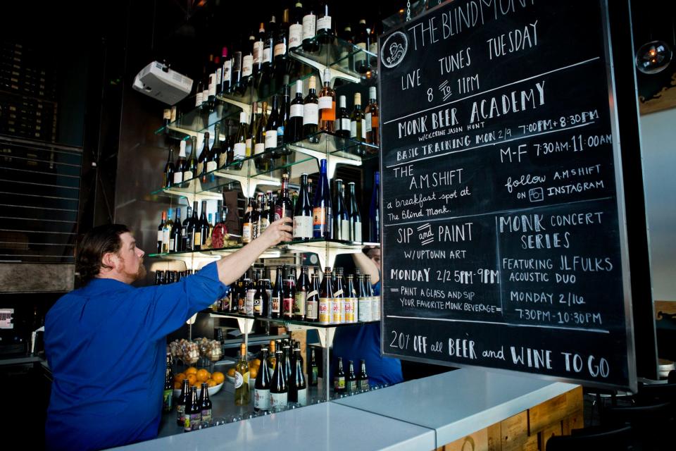 A worker arranges bottles behind the bar at The Blind Monk in West Palm Beach.