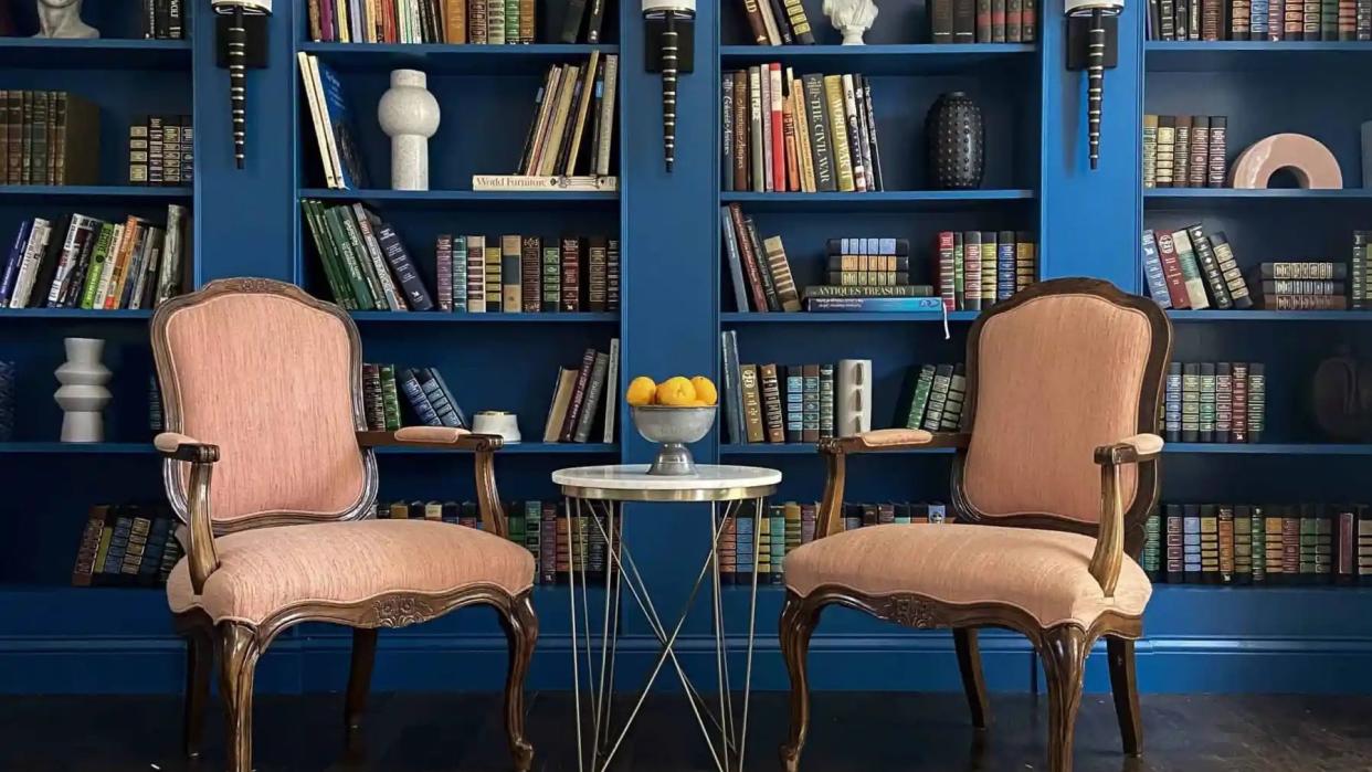 a couple chairs in front of a book shelf