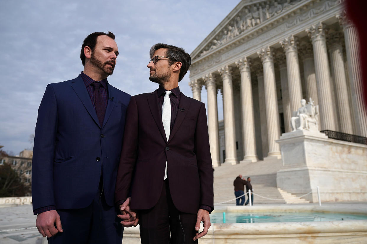 Charlie Craig (left) and Dave Mullins (right), the gay couple who were denied having their wedding cake baked by cake artist Jack Phillips, look at each other during an interview in front of the U.S. Supreme Court on Dec. 5, 2017. (Photo: Alex Wong via Getty Images)