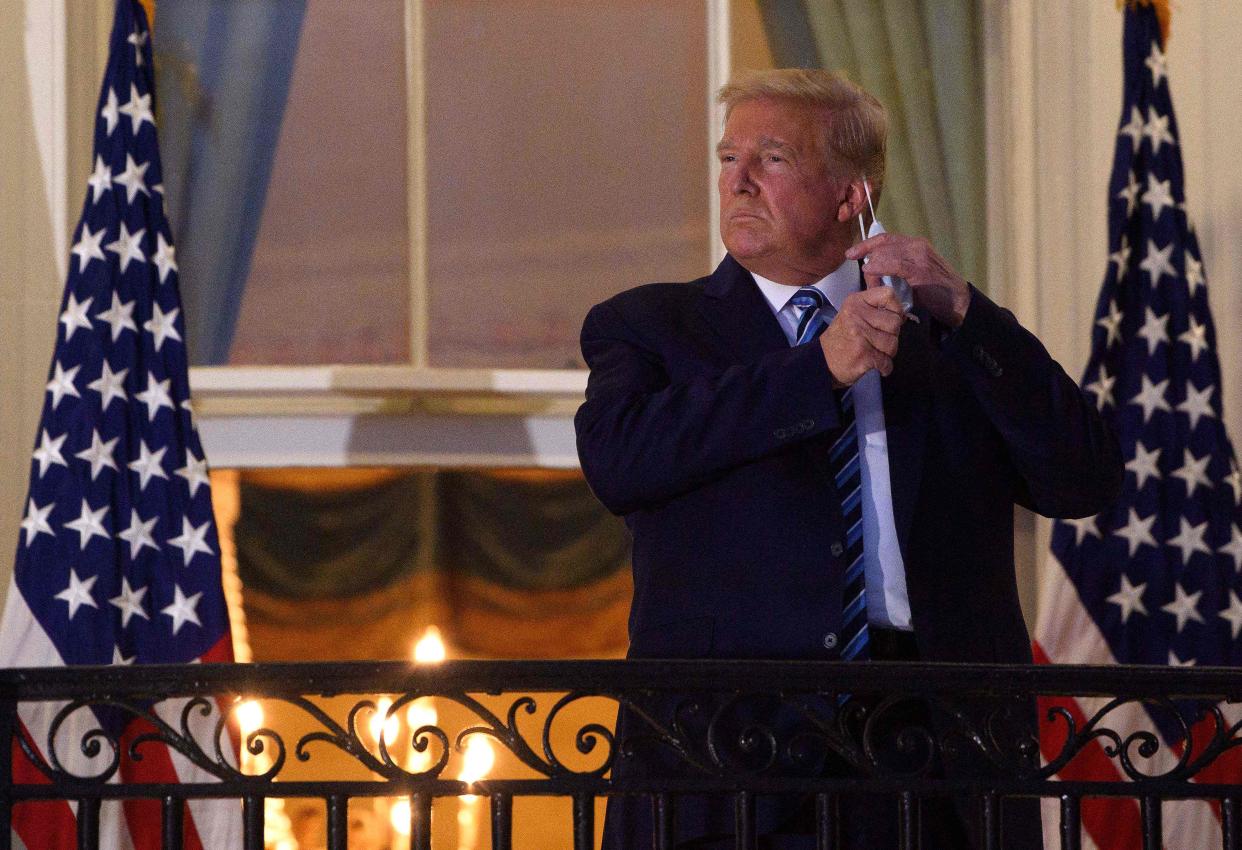 <p>File Image: In this file photo taken on 5 October, 2020, US president Donald Trump takes off his face mask as he arrives at the White House upon his return from Walter Reed Medical Center, where he underwent treatment for Covid-19, in Washington, DC.</p> (AFP via Getty Images)