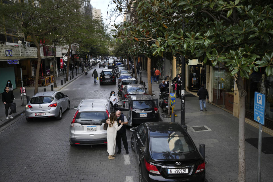 A couple hug each other as other people pass at Hamra Street, in Beirut, Lebanon, Wednesday, Jan. 12, 2022. Hamra Street once was home to the region's top movie theaters, shops selling international brands and cafes where intellectuals from around the Arab world gathered. Today, it reflects Lebanon's devastating multiple crises, with shuttered stores, beggars and piles of trash on the corners. (AP Photo/Hussein Malla)