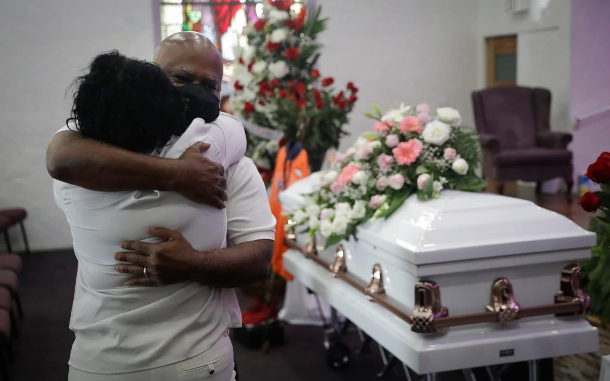 Two relatives hug during a funeral service for Lydia Nunez, who died of Covid-19, at the Metropolitan Baptist Church in Los Angeles - Marcio Jose Sanchez /AP