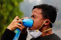 A youth inhales an oxygen-can as he being treatmented during a Global Climate Strike rally as smog covers the city due to the forest fires in Palangka Raya