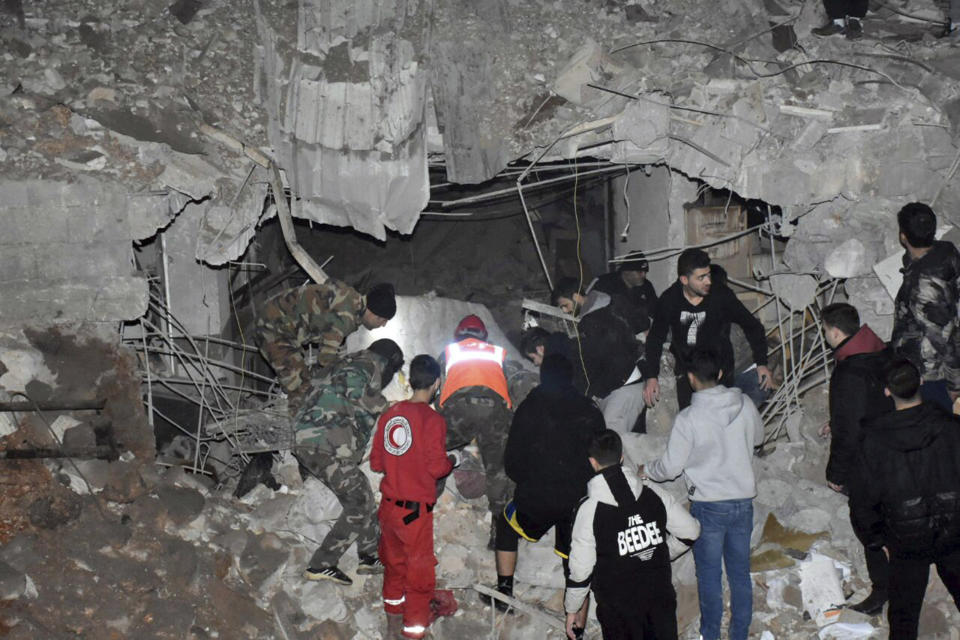 In this photo released by the Syrian official news agency SANA, Syrian security forces and civil defence workers search for victims under the rubble of a building that was destroyed by Israeli airstrikes, in Homs, Syria, late Tuesday, Feb. 6, 2024. Syria's military says Israeli airstrikes over the central city of Homs and nearby areas have killed and wounded civilians. (SANA via AP)