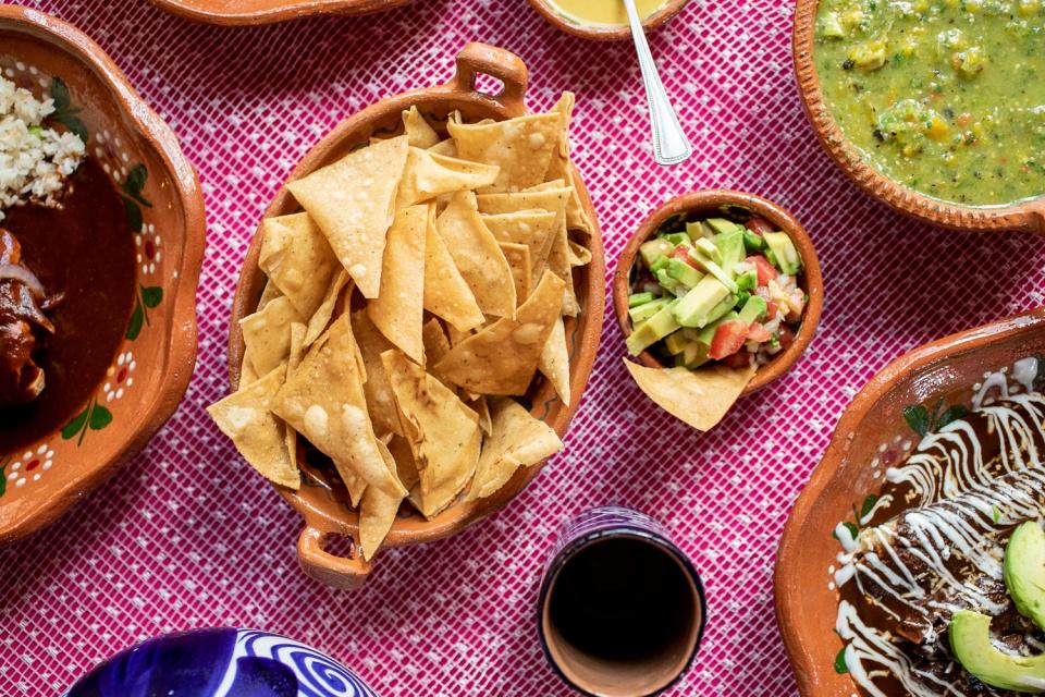 Tortilla chips, sliced avocado, and other dishes on a table.