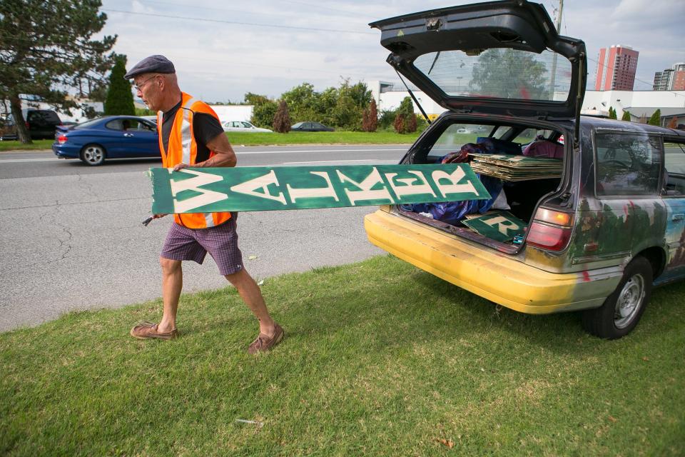 Scott Walker pulling out a homemade political sign from his vehicle in 2018.