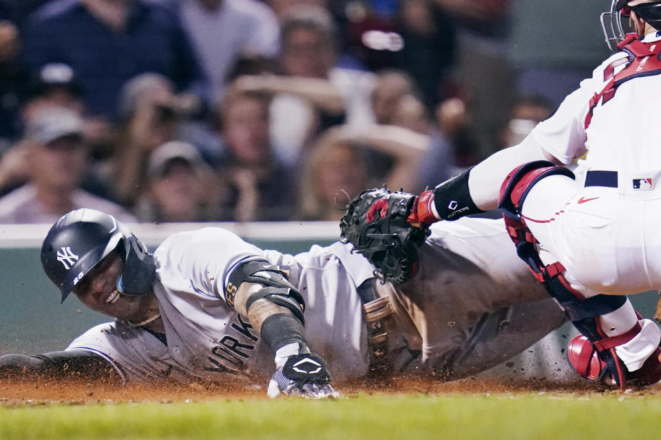 New York Yankees' Gleyber Torres smiles while sliding home safely on a throwing error by Boston Red Sox catcher Connor Wong, after driving in Aaron Judge and Aaron Hicks on a single, during the fifth inning of a baseball game at Fenway Park, Wednesday, Sept. 14, 2022, in Boston. (AP Photo/Charles Krupa)