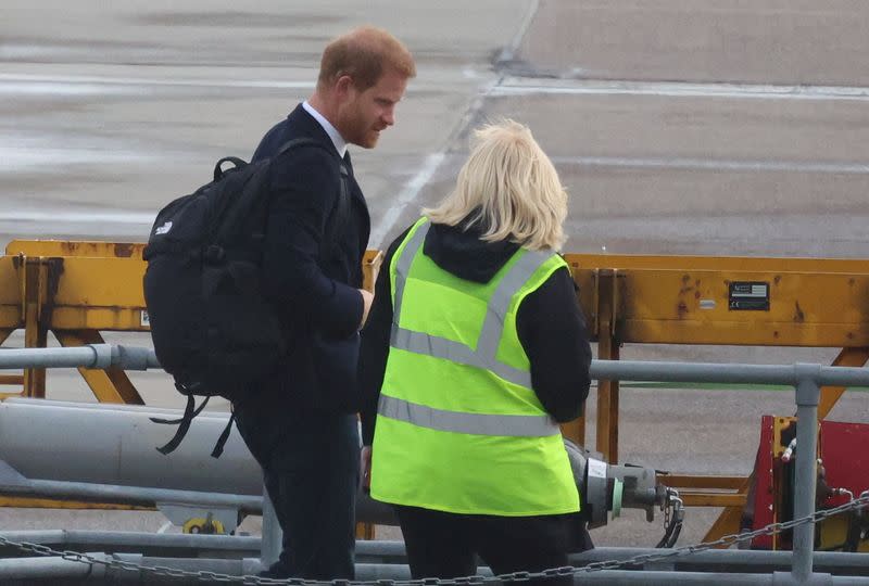 Prince Harry comforts an airport worker who had expressed her sympathy while accompanying him across the tarmac in Aberdeen.