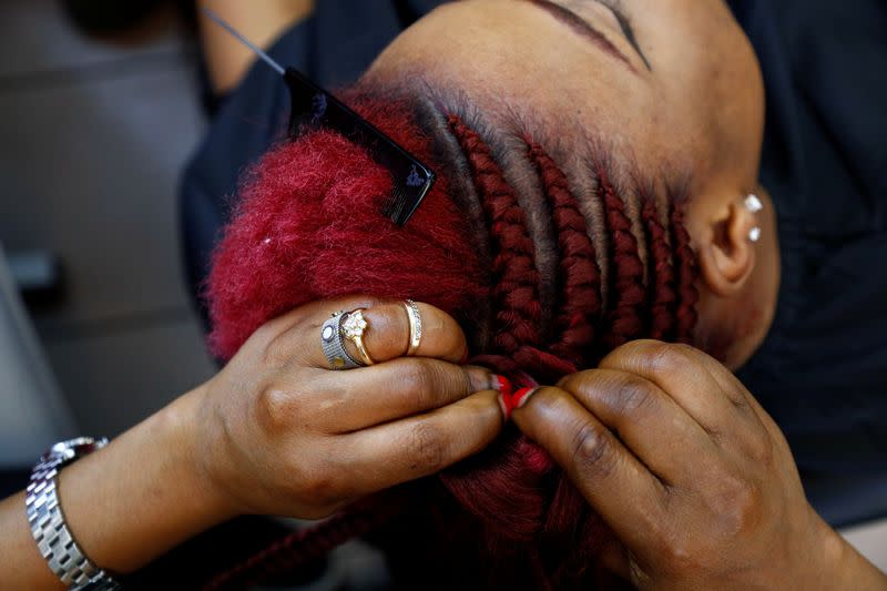 A hairdresser braids the hair of a client in a hair salon at the Matonge gallery in Brussels