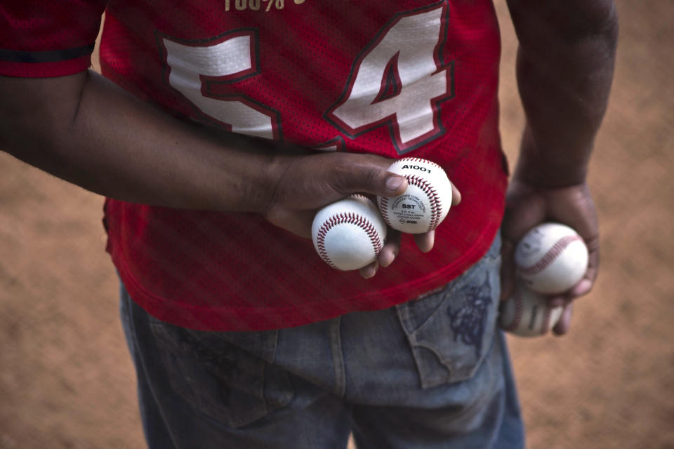 A man holds extra baseballs on the sidelines of an exhibition game between last year's college championship team from the University of Tampa and a Cuban youth squad in Havana, Cuba, Wednesday, Jan. 15, 2014. For one day at least, the heated rhetoric that often characterizes the divide between Havana and Washington was set aside in favor of an umpire's strike calls and the crack of the bat. (AP Photo/Ramon Espinosa)