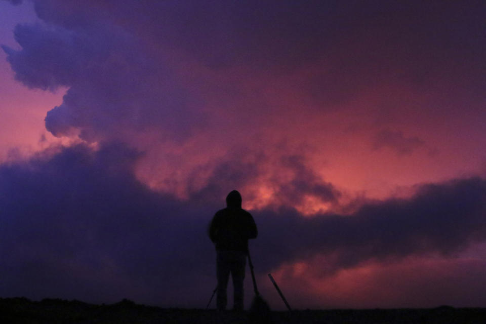 A man photographs the glow from lava erupting from Hawaii's Mauna Loa volcano, Monday, Nov. 28, 2022, in Hilo, Hawaii. (AP Photo/Caleb Jones)