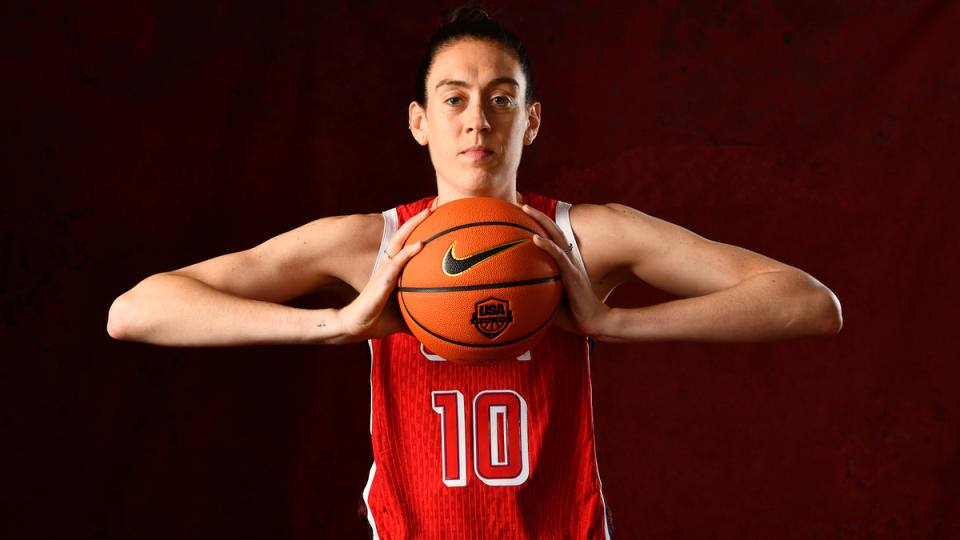 A basketball player wearing a number 10 jersey poses with a basketball in front of his chest