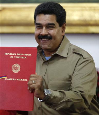 Venezuelan President Nicolas Maduro receives the document approving a law which grants him with decree powers in Caracas, November 19, 2013. REUTERS/Carlos Garcia Rawlins