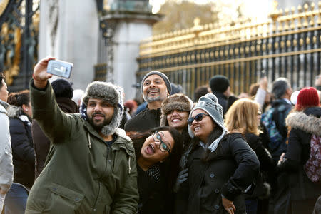 FILE PHOTO: Tourists take pictures outside Buckingham Palace after Prince Harry announced his engagement to Meghan Markle, in London, Britain, November 27, 2017. REUTERS/Darrin Zammit Lupi/File Photo