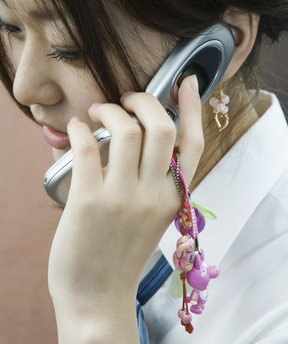 Young woman using cellphone decorated with charms