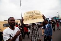 A follower of opposition leader Martin Fayulu holds up a sign reading “scam of the century = RAM”, during a protest over the independence of the country’s electoral commission, in Kinshasa