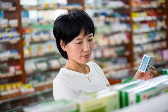 <p>Longhua Liao / Getty Images</p> An Asian woman buys medicine at a pharmacy
