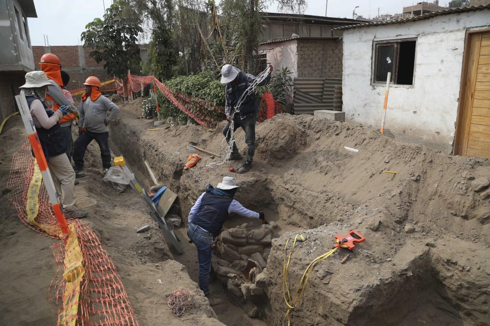 En esta foto del 12 de febrero de 2020, arqueólogos y trabajadores de gas se encuentran en el sitio donde se descubrieron huesos y vasijas antiguas de una cultura preincaica durante la excavación de una nueva línea de gas natural a través del barrio Puente Piedra de Lima, Perú. (AP Foto / Martín Mejía)