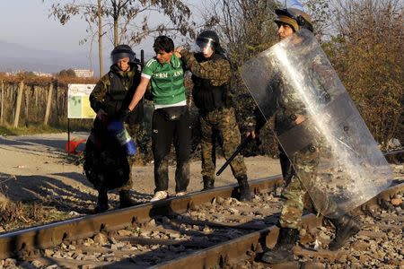 An Iranian migrant is escorted back to Greece by Macedonian policemen after he tried to cross Greece's border with Macedonia illegally, near the Macedonian town of Gevgelija, November 19, 2015. REUTERS/Alexandros Avramidis