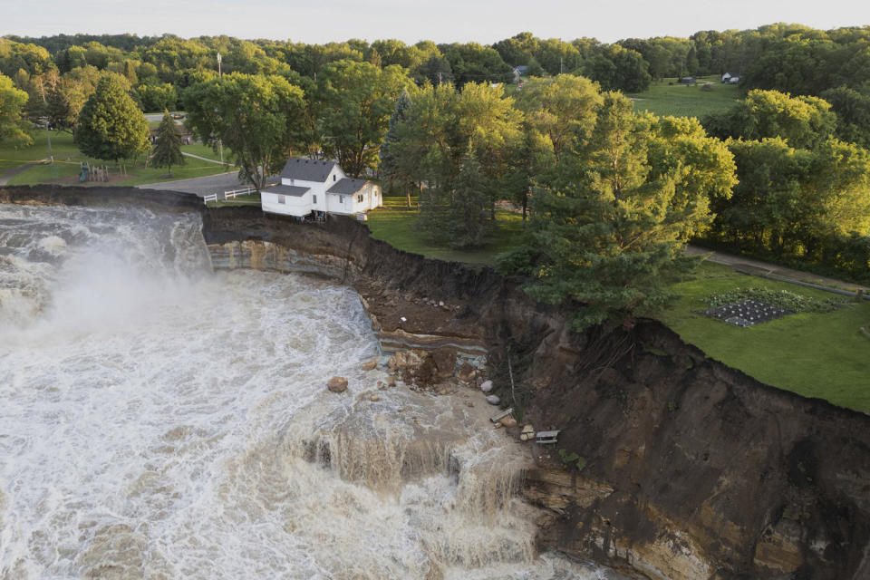 A house teeters before partially collapsing into the Blue Earth River at the Rapidan Dam in Mankato, Minnesota.  (Andrew Weinzierl/AW Aerial via AP)