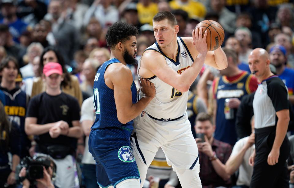 Denver Nuggets center Nikola Jokic, right, looks to drive to the basket as Minnesota Timberwolves center Karl-Anthony Towns defends in the first half of an NBA basketball game Friday, April 1, 2022, in Denver. (AP Photo/David Zalubowski)