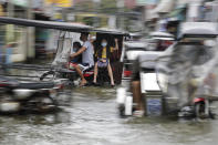 Residents wearing masks to prevent the spread of the coronavirus ride motorcycles as they negotiate a flooded road due to Typhoon Molave in Pampanga province, northern Philippines on Monday, Oct. 26, 2020. A fast moving typhoon has forced thousands of villagers to flee to safety in provinces. (AP Photo/Aaron Favila)