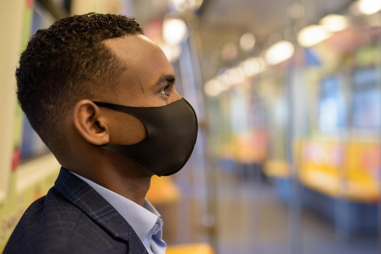Portrait of young African businessman with mask for protection from corona virus outbreak social distancing inside the train