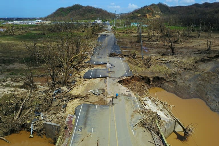 A man rides his bicycle on a damaged road in Toa Alta, west of San Juan, Puerto Rico