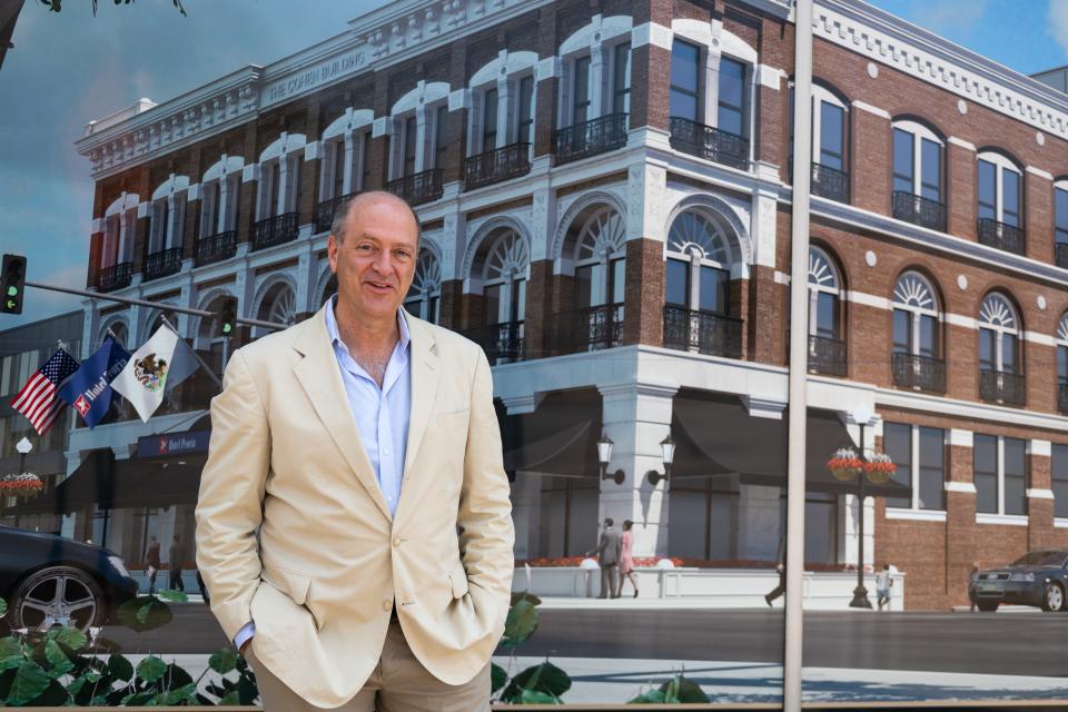 Les Cohen stands in front of a photo rendering of the renovated Cohen Furniture Company building on Thursday, July 2, 2021. The building has been in Cohen's family for over a century.