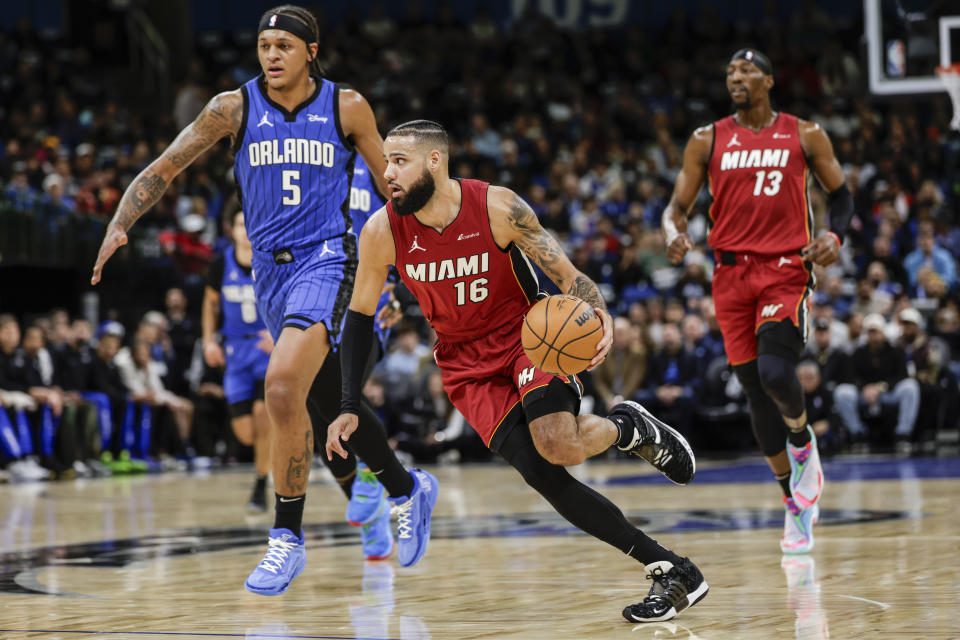 Miami Heat forward Caleb Martin (16) drives against Orlando Magic forward Paolo Banchero (5) during the first half of an NBA basketball game, Wednesday, Dec. 20, 2023, in Orlando, Fla. (AP Photo/Kevin Kolczynski)