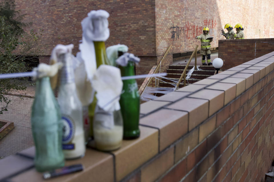 Fire and Rescue teams check campus littered with unused molotov cocktails at the Polytechnic University campus in Hong Kong, Thursday, Nov. 28, 2019. Police safety teams Thursday began clearing a university that was a flashpoint for clashes with protesters, and an officer said any holdouts still hiding inside would not be immediately arrested. (AP Photo/Ng Han Guan)