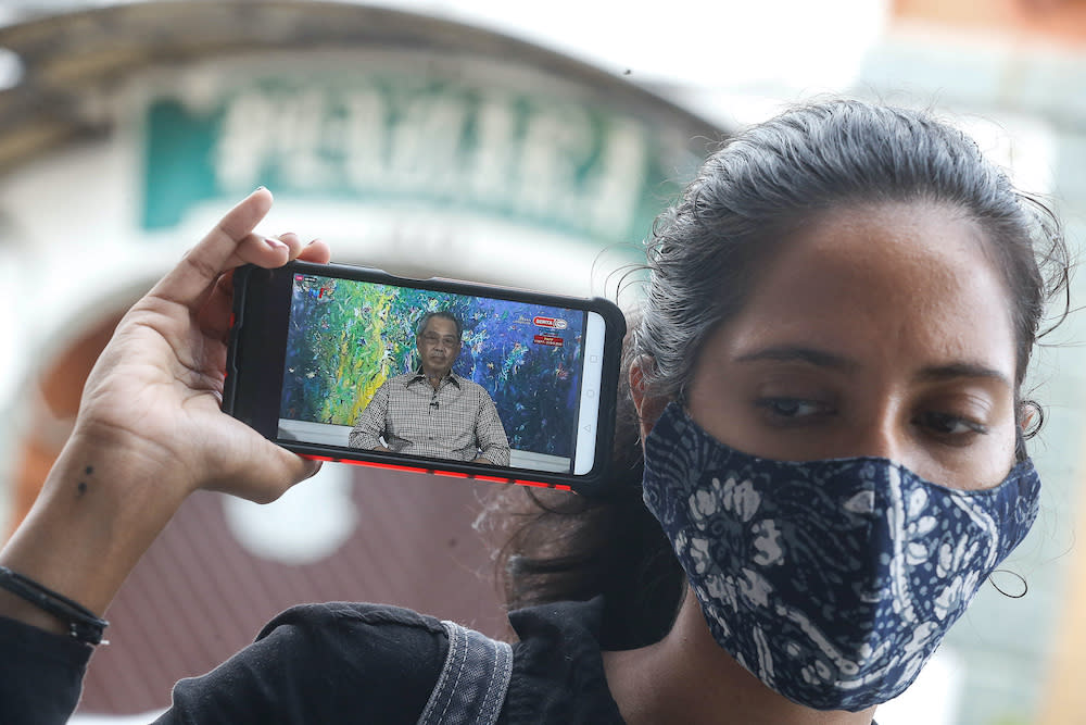 A woman listens to the special announcement by Prime Minister Tan Sri Muhyiddin Yassin on her smartphone, October 6, 2020. — Picture by Sayuti Zainudin