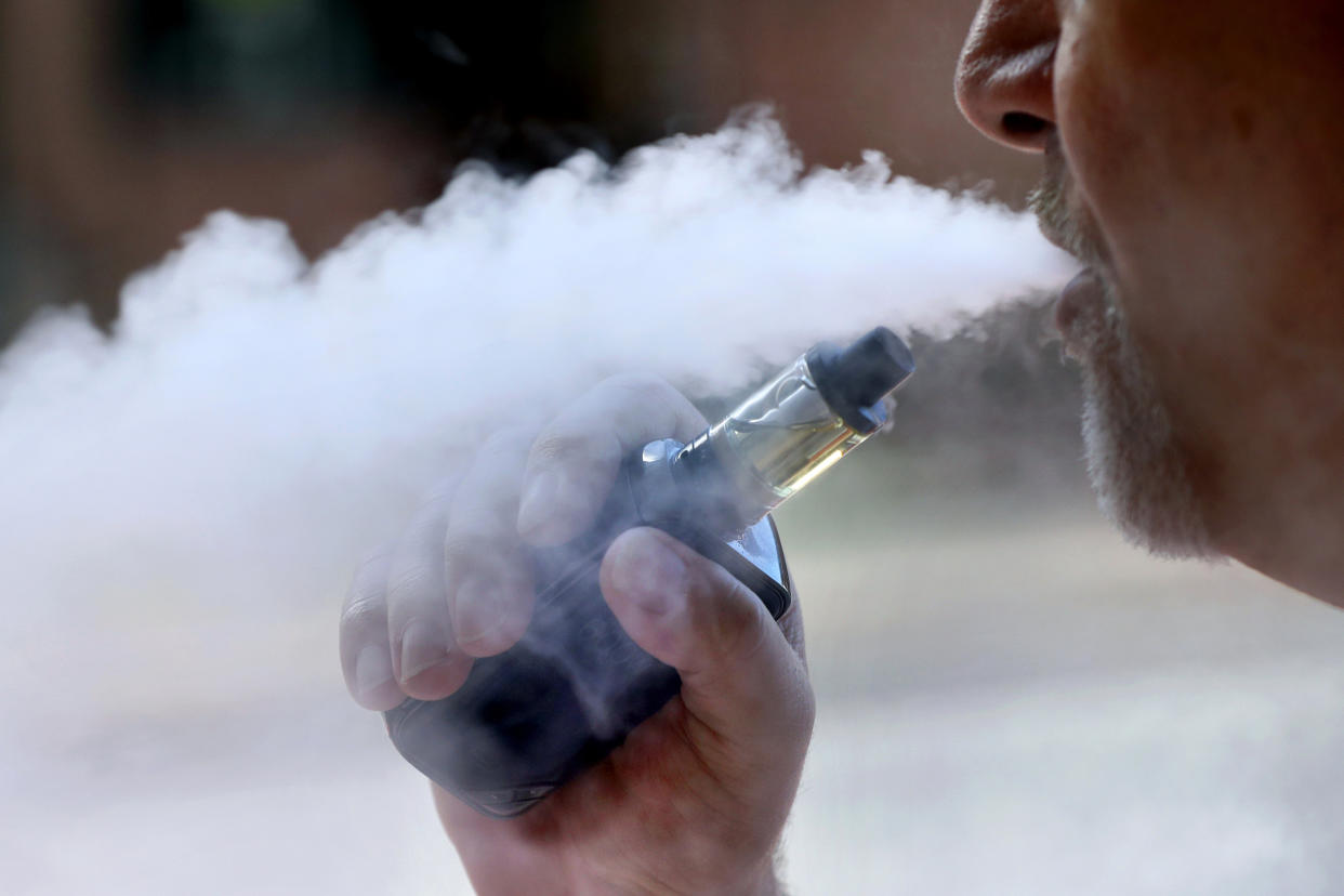 FILE  - In this Aug. 28, 2019, file photo, a man exhales while smoking an e-cigarette in Portland, Maine. Walmart says it will stop selling electronic cigarettes at its namesake stores and Sam's Clubs following a string of illnesses and deaths related to vaping.  The nation's largest retailer said Friday, Sept. 20 that it will complete its exit from e-cigarettes after selling through current inventory. It cited growing federal, state and local regulatory complexity regarding vaping products. (AP Photo/Robert F. Bukaty, File)