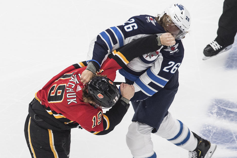 Winnipeg Jets' Blake Wheeler (26) and Calgary Flames' Matthew Tkachuk (19) fight during the first period of an NHL hockey playoff game in Edmonton, Alberta, Saturday, Aug. 1, 2020. (Jason Franson/The Canadian Press via AP)