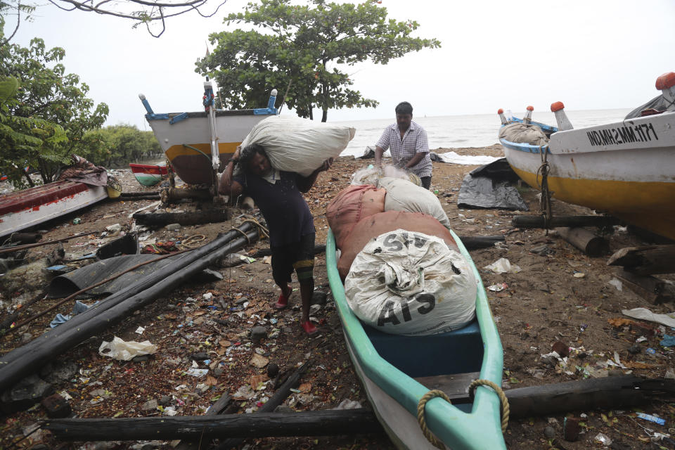 Fishermen load their nets onto a boat to keep them safe by the shores of the Arabian Sea in Mumbai, India, Wednesday, June 3, 2020. A storm in the Arabian Sea off India's west coast intensified into a severe cyclone on Wednesday, gathering speed as it barreled toward India's financial capital of Mumbai. Nisarga was forecast to drop heavy rains and winds gusting up to 120 kilometers (75 miles) per hour when it makes landfall Wednesday afternoon as a category 4 cyclone near the coastal city of Alibagh, about 98 kilometers (60 miles) south of Mumbai, India's Meteorological Department said. (AP Photo/Rafiq Maqbool)