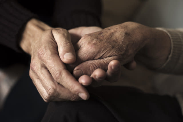 young man holding the hand of an old woman