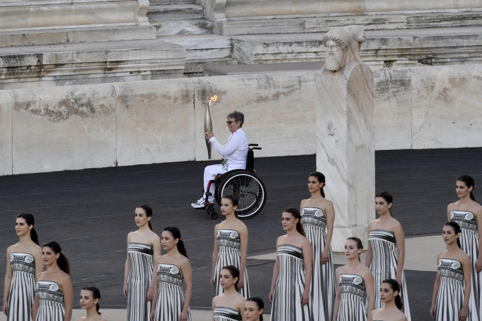 Beatrice Hess, France's greatest Paralympic champion, carries the Olympic flame during the flame handover ceremony at Panathenaic stadium, where the first modern games were held in 1896, in Athens, Friday, April 26, 2024. On Saturday the flame will board the Belem, a French three-masted sailing ship, built in 1896, to be transported to France.(AP Photo/Vasilis Psomas)
