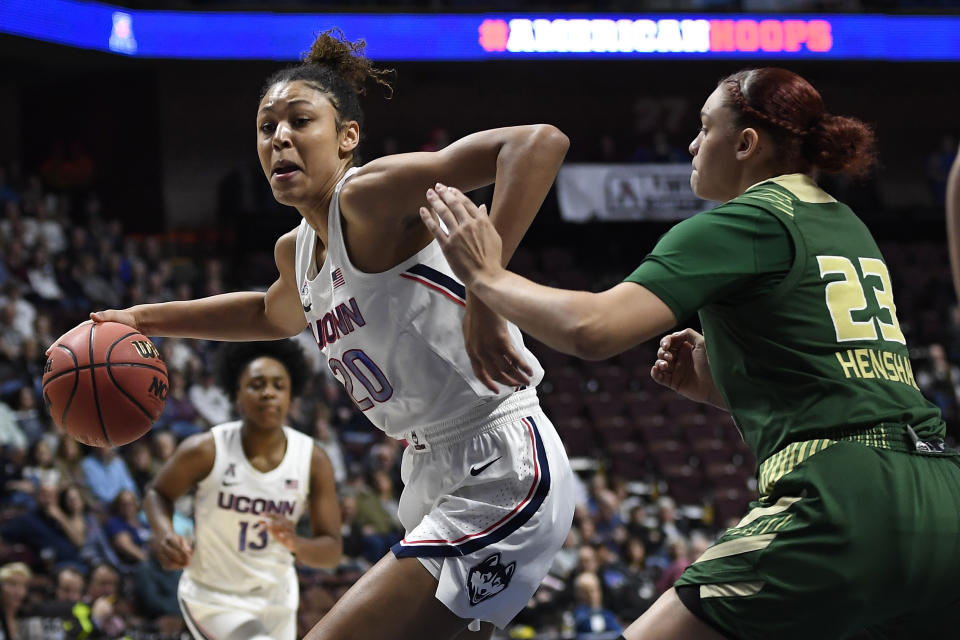 FILE - Connecticut's Olivia Nelson-Ododa, left, drives around South Florida's Tamara Henshaw during the first half of an NCAA college basketball game in the American Athletic Conference tournament semifinals at Mohegan Sun Arena, Sunday, March 8, 2020, in Uncasville, Conn. UConn officials have discussed creating helmet stickers, warm-up T-shirts and altering athletic uniforms in other ways to show support for the Black Lives Matter movement. “I believe as athletes that we have this platform, especially here, we have a platform and a voice and we should use it, especially on topics like this that have been going on for hundreds of years," center Olivia Nelson-Ododa said last month. "And so the ability to speak out about it and advocating for the Black Lives Matter movement is very important to me, and I know for the rest of my team as well.” (AP Photo/Jessica Hill, File)