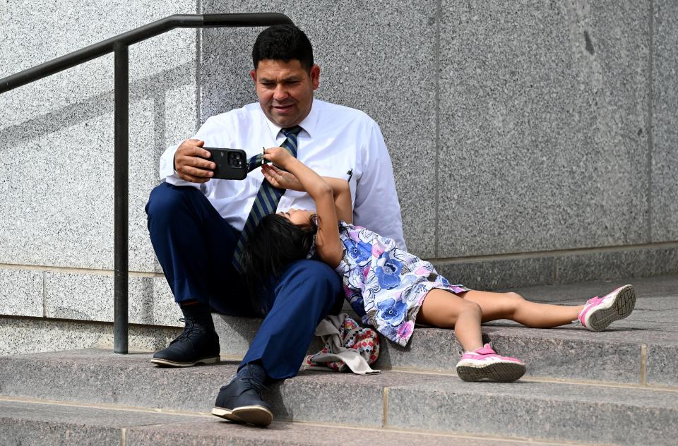Enrique Martinez watches conference on his phone while sitting outside with his daughter Rebecca Martinez during the Saturday afternoon session of the 193rd Semiannual General Conference of The Church of Jesus Christ of Latter-day Saints at the Conference Center in Salt Lake City on Saturday, Sept. 30, 2023. | Scott G Winterton, Deseret News